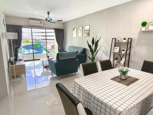 a dining room with a table and chairs and a living room at Cozy Suite Pool View@Ipoh Waterpark FREE (WI-FI)&Netflix Station 18 pengkalan Manhattan in Ipoh