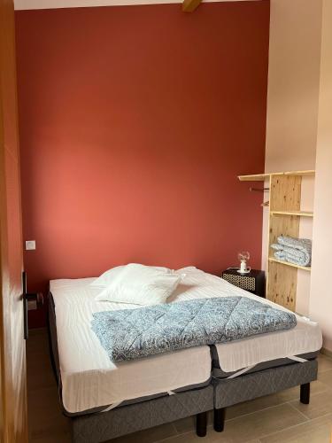 Ce lit se trouve dans une chambre dotée d'un mur rouge. dans l'établissement eco nature, gite à la ferme, à Vendays-Montalivet