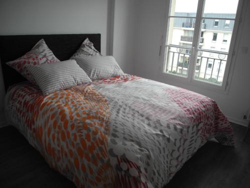 un letto con piumone arancione e bianco e una finestra di Apt Standing Bordeaux Chartrons a Bordeaux