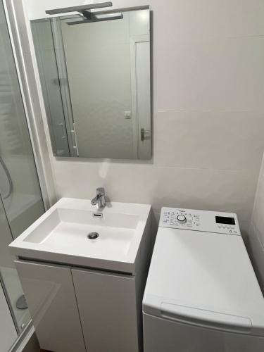 W białej łazience znajduje się umywalka i lustro. w obiekcie Vivez le Bonheur - Plage - Port de plaisance - Vue mer w Hawrze