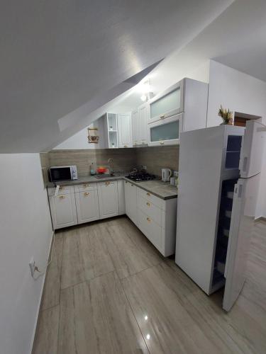 a kitchen with white cabinets and white appliances at Casa Cristina in Cîrţişoara