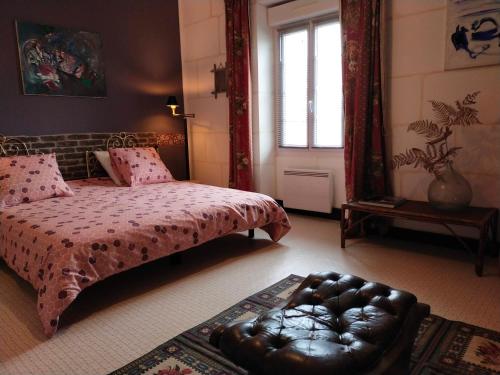 a bedroom with a bed and a leather ottoman at Le jardin Renard-Clos sur Loir cottage in the Loir & Loire valleys in La Chapelle-aux-Choux