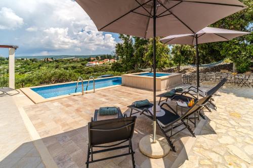 a patio with chairs and an umbrella and a pool at Villa Maria Škrip in Škrip