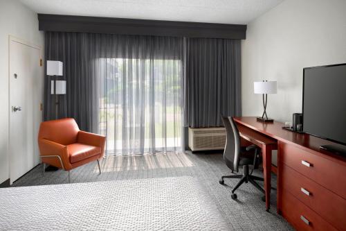 Habitación de hotel con escritorio, silla y TV. en Courtyard Philadelphia Valley Forge / King of Prussia, en Wayne