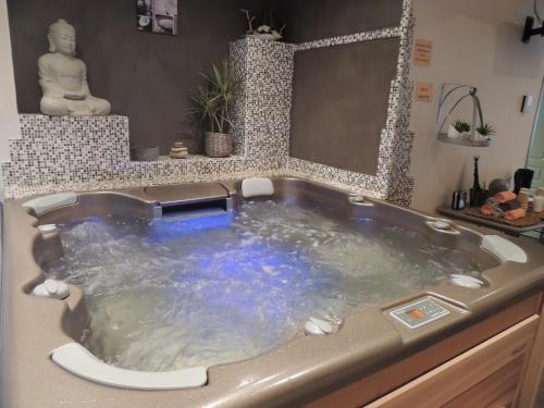 La salle de bains est pourvue d'une baignoire jacuzzi et d'une statue. dans l'établissement Logis Central Hôtel & Spa, à Bort-les-Orgues