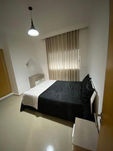 a bedroom with a black bed and a window at ASILAH MARINA GOLF in Asilah