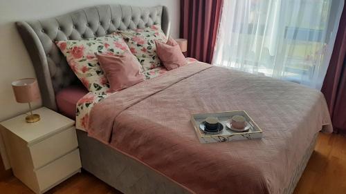 a bed with a tray with two cups on it at Apartman Reina in Soko Banja