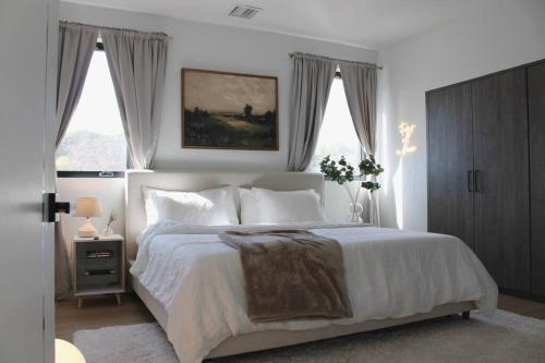 a bedroom with a large white bed with windows at Brand NEW Luxury 2bd Townhouse Pet-Friendly FREE Parking in Los Angeles
