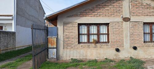 una vieja casa de ladrillo con dos ventanas y una valla en Los girasoles en Esquel