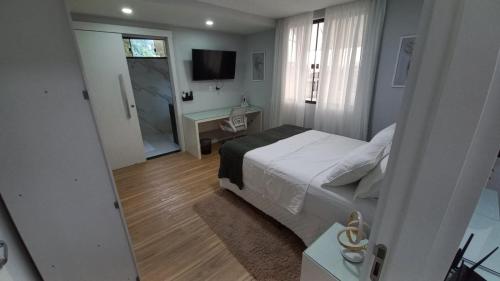 um quarto com uma cama, uma secretária e uma televisão em Studio Praia do Jardim 1 305B em Angra dos Reis