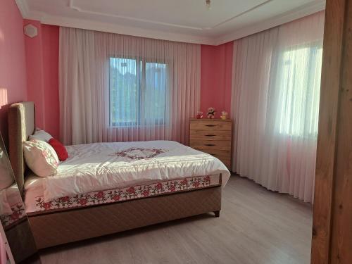 a bedroom with pink walls and a bed and a dresser at Yılmaz Villa in Macka