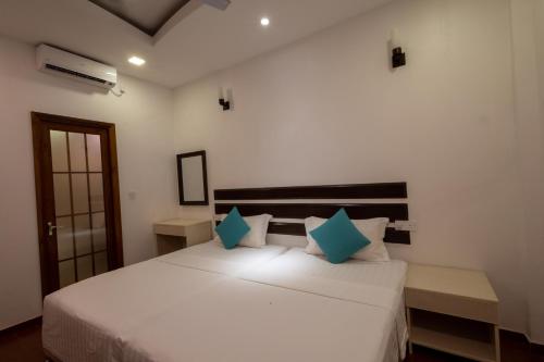 a bedroom with a white bed with blue pillows at LVIS Village in Dharavandhoo