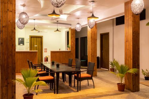 a dining room with a table and chairs and potted plants at LVIS Village in Dharavandhoo