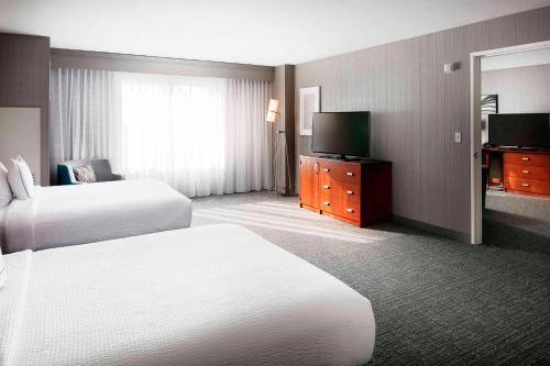 a hotel room with two beds and a flat screen tv at Courtyard Indianapolis Downtown in Indianapolis