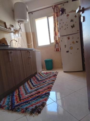 cocina con alfombra en el suelo junto a una nevera en Appartement calme au centre en Oujda