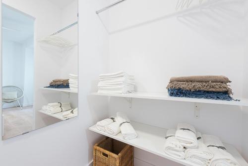 a room with white shelves with towels and a mirror at SlowHome Catedral in Almería