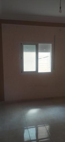 une chambre vide avec une fenêtre dans un mur blanc dans l'établissement مدينه صفرو المغرب, à Séfrou