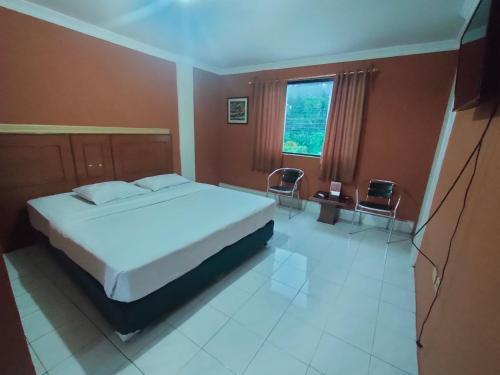 a bedroom with a bed and two chairs and a window at Hotel Syariah Taman Cibinong 2 By FPH 