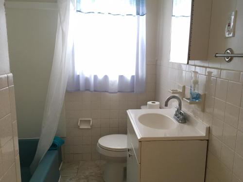 baño con lavabo y aseo y ventana en Blue Haven Apartments, en Ocean City