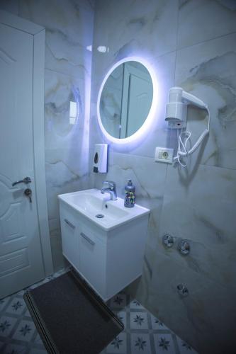 a white bathroom with a sink and a mirror at Vila Visi Hotel in Korçë