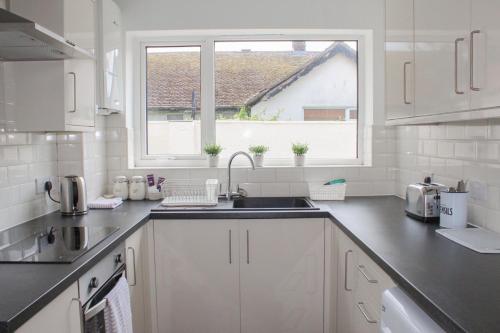 a white kitchen with a sink and a window at Lovely Bungalow Close to Beach in Prestatyn