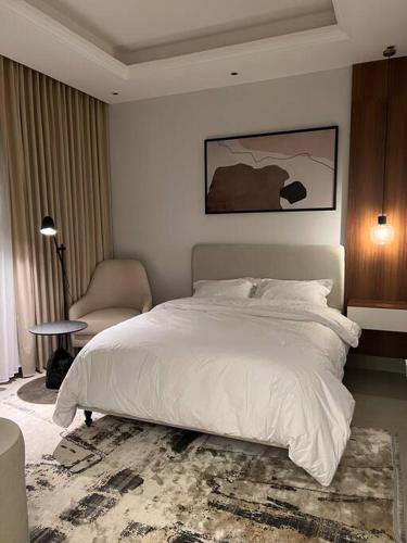 ein Schlafzimmer mit einem großen weißen Bett und einem Stuhl in der Unterkunft New apartment, two entrances in Riad