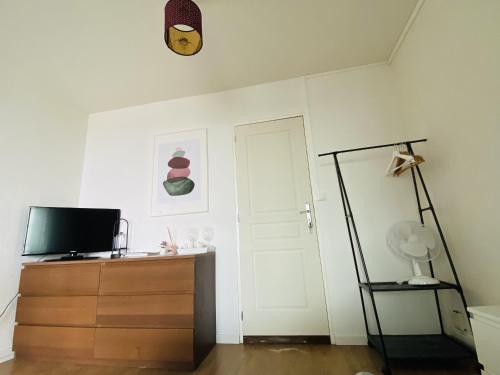 Cette chambre dispose d'une télévision, d'une commode et d'une porte. dans l'établissement Chambre privée avec petit salon extérieur, à Bordeaux