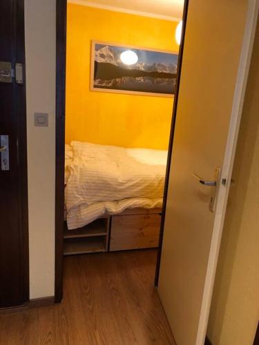 - une petite chambre avec un lit dans un mur jaune dans l'établissement Chamonix centre - 2 pièces 32 m2, à Chamonix-Mont-Blanc