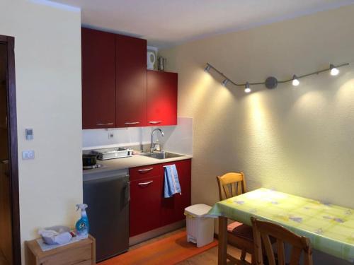 une cuisine avec des placards rouges et une table avec une table dans l'établissement Chamonix centre - 2 pièces 32 m2, à Chamonix-Mont-Blanc