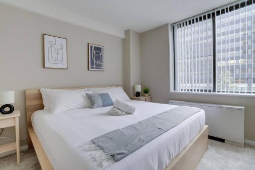 a white bedroom with a large bed and a window at Wonderful 2BR Condo @Crystal City With Gym in Arlington