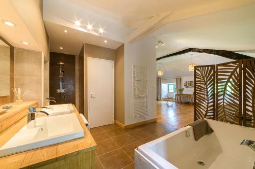 ein großes Bad mit einer Badewanne und einem Waschbecken in der Unterkunft MANOIR Le Moulinal47 - vue panoramique in Courbiac