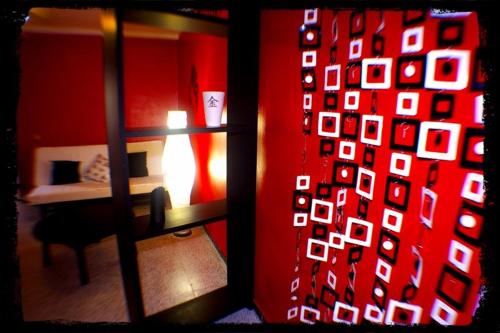 a room with a red wall with a bed and a window at Pensión El Alamo in Lepe