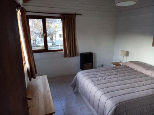 um quarto com uma cama, uma janela e uma televisão em Casagrande em Esquel