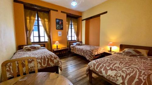 Habitación de hotel con 2 camas y mesa en La Posada Colonial, en Quito