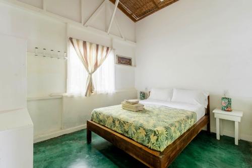 a white bedroom with a bed and a window at Bajo el Arbol B&B in Santa Teresa Beach