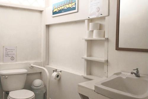 a white bathroom with a toilet and a sink at Bajo el Arbol B&B in Santa Teresa Beach