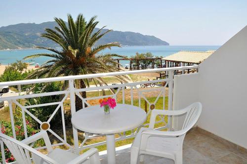 una mesa blanca y sillas en un balcón con vistas al océano en Vrachos Pension en Afionas