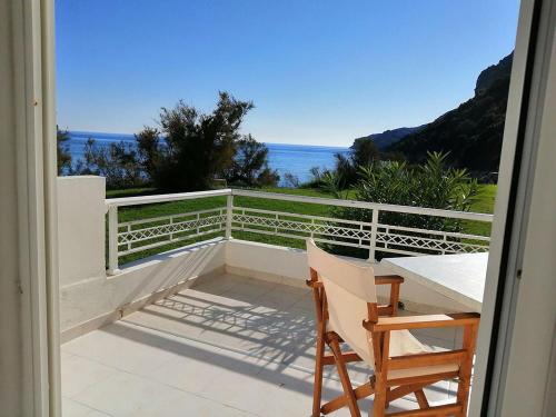 balcón con mesa, sillas y vistas al océano en Vrachos Pension en Afionas