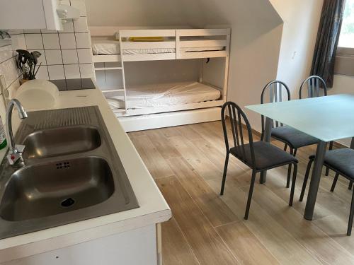 a kitchen with a sink and a table with chairs at Chouette appartement 5 personnes in De Haan