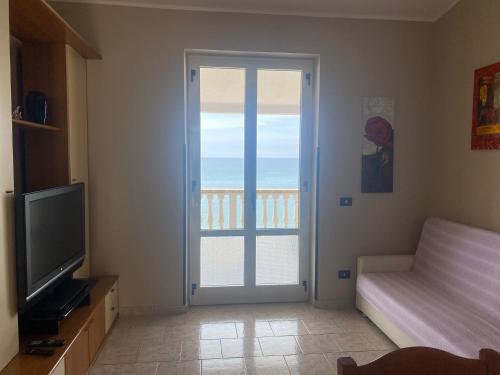 a living room with a television and a sliding glass door at Casa sul mare in Ovile la Marinella