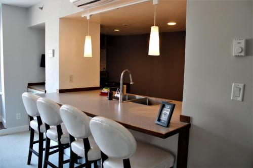 a kitchen with a bar with white chairs and a sink at 1BR Resort View at the base of Whistler in Whistler