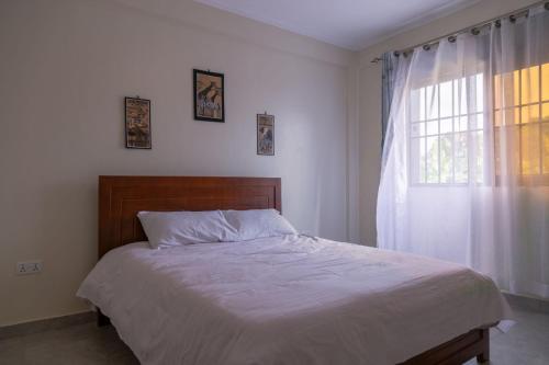 a bedroom with a large bed with a window at Eric and Devota apartments Kampala in Buwate