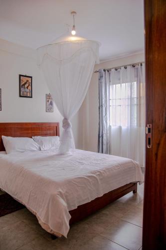 a bedroom with a white bed and a window at Eric and Devota apartments Kampala in Buwate