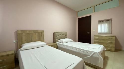 a bedroom with two beds and a mirror at Ona’s Apartments in Lushnjë