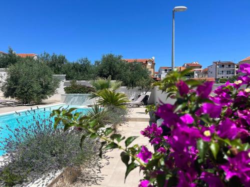 a view of a swimming pool with purple flowers at Apartments and Rooms Mateša in Vodice