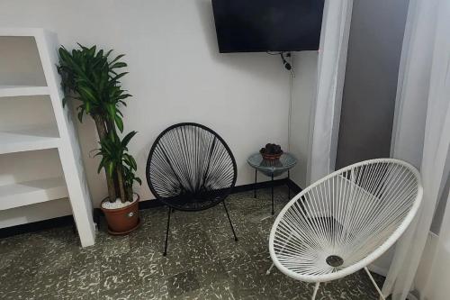 カルタヘナ・デ・インディアスにあるHotel M4 Económico Estándarの白い椅子2脚とファンが備わる客室です。