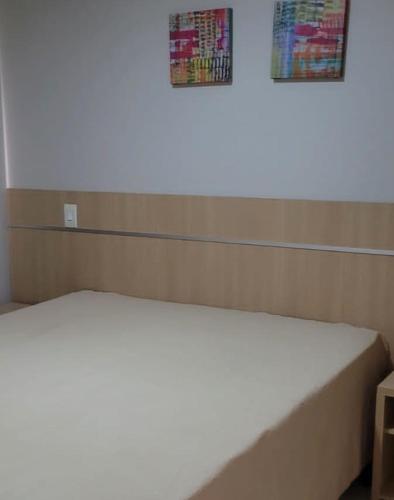 a bed in a room with a wall with two pictures at Apartamento da Gigi Caldas in Caldas Novas