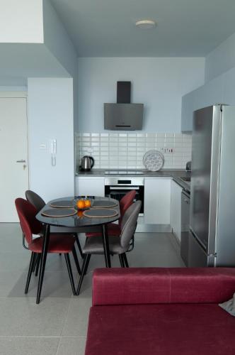 a kitchen with a table and some red chairs at Seaview apartments in Ayios Elias