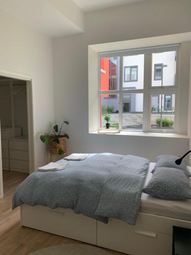 a white bedroom with a bed and a window at Apartment in Breiviken in Bergen