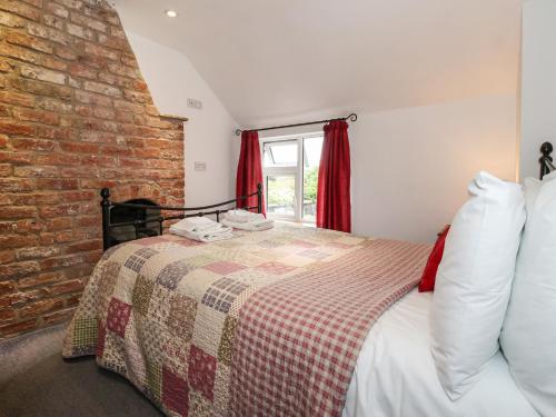 um quarto com uma cama e uma parede de tijolos em The Cottage em Great Driffield